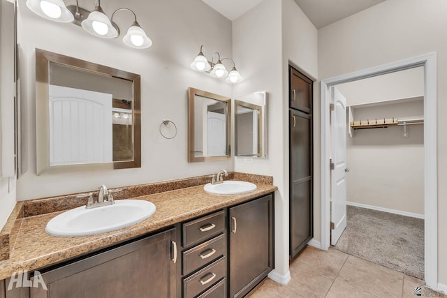 bathroom featuring double vanity, tile patterned floors, a spacious closet, and a sink