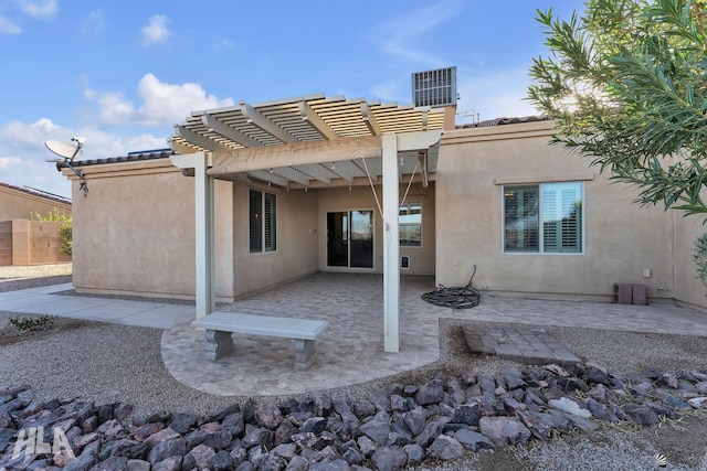 rear view of property featuring a pergola, stucco siding, and a patio area