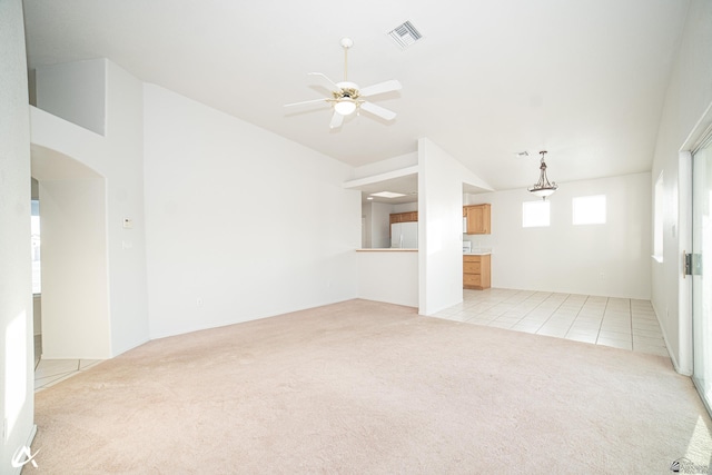 unfurnished living room featuring visible vents, a ceiling fan, lofted ceiling, and light carpet