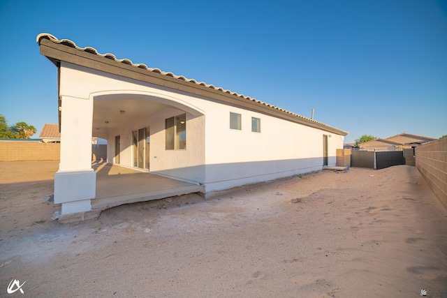 rear view of house with a fenced backyard, stucco siding, and a patio area