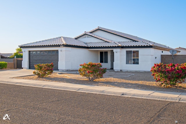 ranch-style house featuring a tile roof, a garage, fence, concrete driveway, and stucco siding