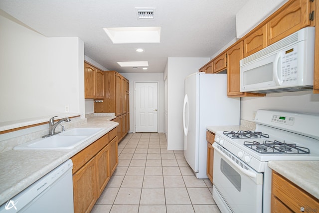 kitchen with visible vents, white appliances, light countertops, a sink, and a skylight