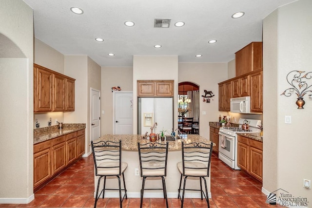 12147 E 33rd St, Yuma, AZ 85367 - kitchen featuring white appliances, arched walkways, a kitchen island with sink, recessed lighting, and visible vents