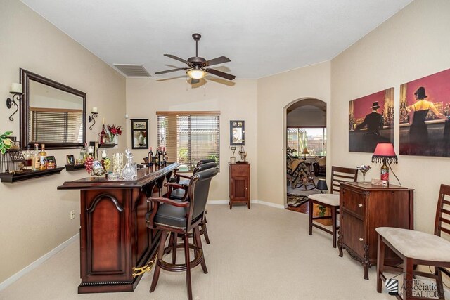 12147 E 33rd St, Yuma, AZ 85367 - bar featuring baseboards, ceiling fan, light colored carpet, a bar, and arched walkways
