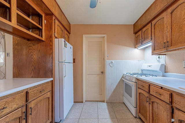 1221 S 10th Ave, Yuma, AZ 85364 - kitchen featuring white appliances, brown cabinetry, light countertops, light tile patterned floors, and a textured wall