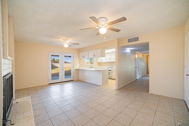 unfurnished living room featuring a textured ceiling, ceiling fan, sink, light tile patterned floors, and a fireplace