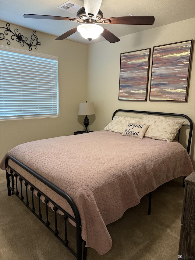 carpeted bedroom featuring a ceiling fan and visible vents