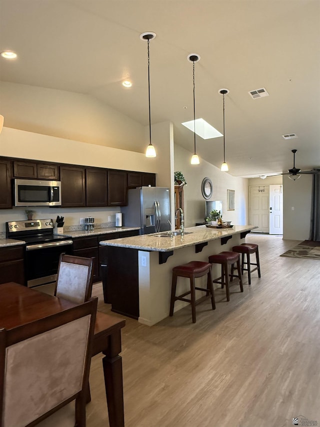kitchen with visible vents, a sink, a breakfast bar, stainless steel appliances, and an island with sink
