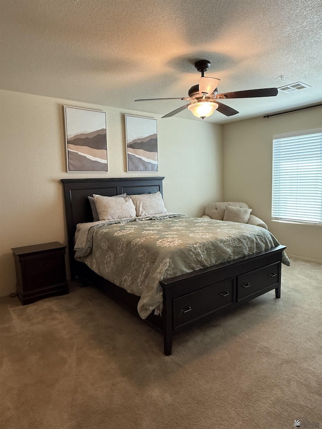 carpeted bedroom featuring visible vents, a ceiling fan, and a textured ceiling