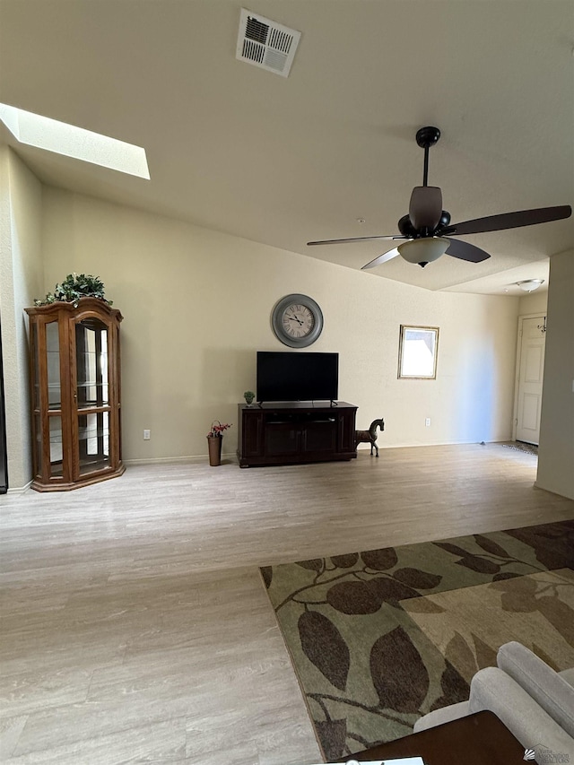 living area featuring a ceiling fan, a skylight, visible vents, and wood finished floors