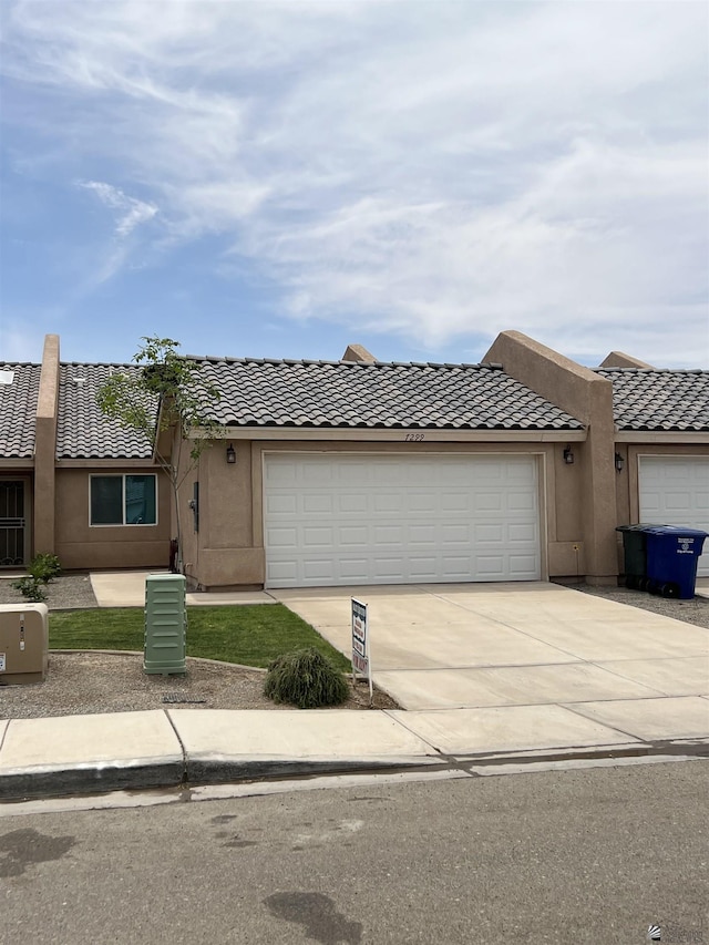 view of front of house with a garage, stucco siding, concrete driveway, and a tile roof