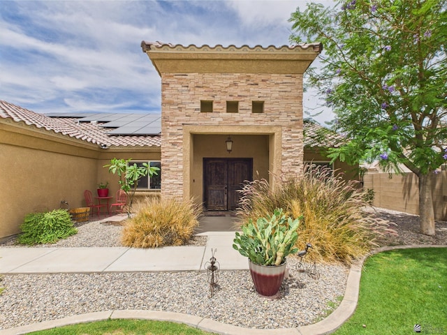 5936 E 39th St, Yuma, AZ 85365 - doorway to property featuring solar panels, stone siding, stucco siding, and a tile roof