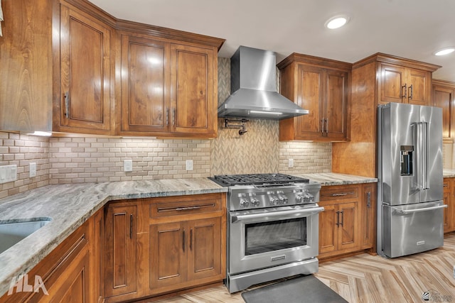 kitchen featuring brown cabinets, high end appliances, and wall chimney exhaust hood