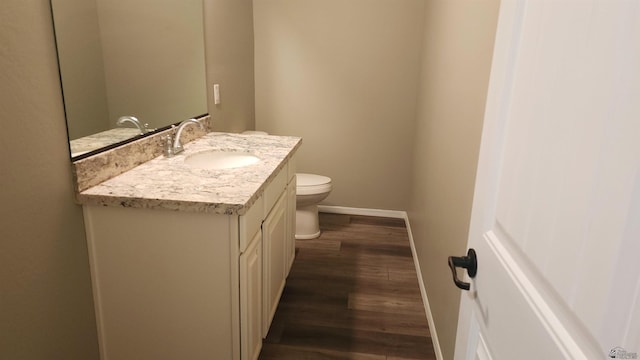 bathroom with baseboards, vanity, toilet, and wood finished floors