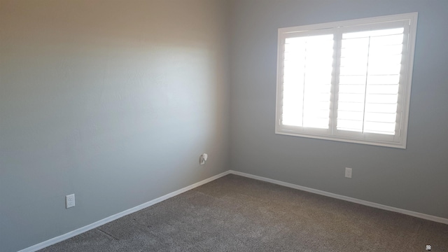 unfurnished room with baseboards and dark carpet