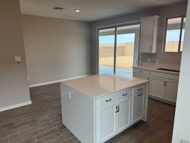 kitchen with a healthy amount of sunlight, white cabinets, dark wood-style floors, and visible vents