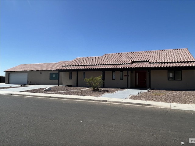 view of front of house with a tiled roof, an attached garage, and stucco siding