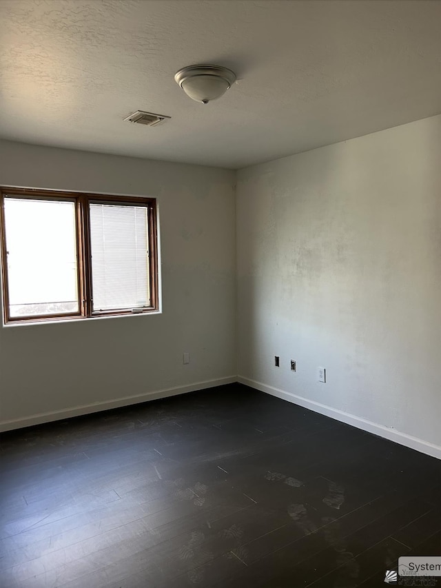 empty room featuring baseboards, visible vents, and dark wood-style floors