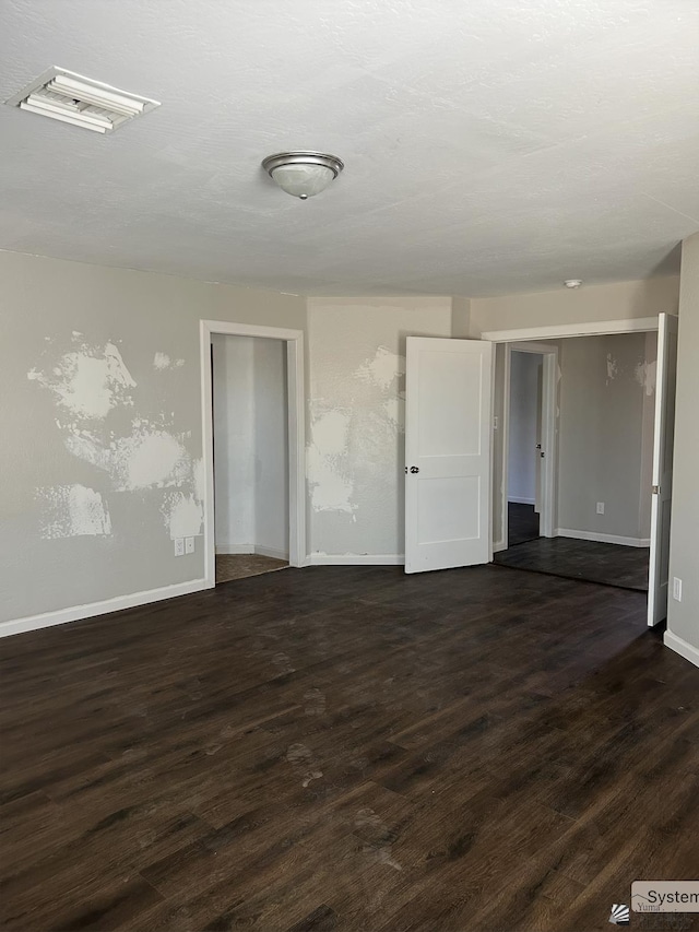 spare room with dark wood-type flooring, baseboards, and visible vents