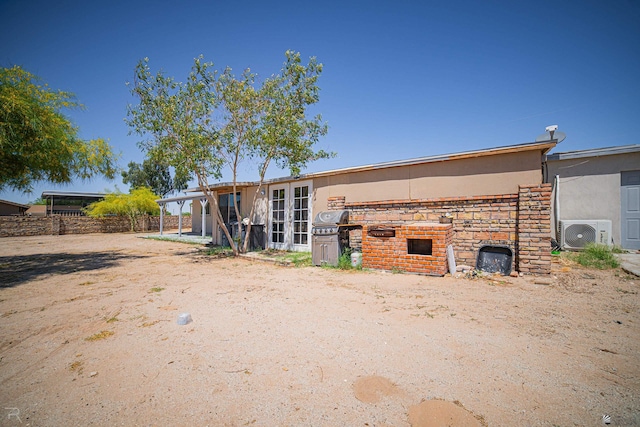 12687 E 42nd Pl, Yuma, AZ 85367 - rear view of house with fence, ac unit, french doors, and stone siding