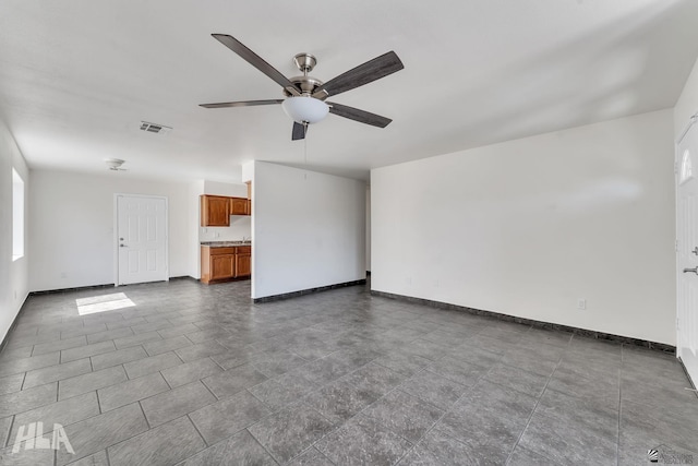 unfurnished living room featuring visible vents, baseboards, and ceiling fan