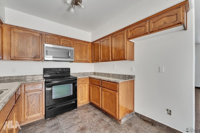 kitchen with brown cabinetry, stainless steel microwave, light countertops, and electric range