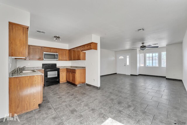 kitchen with stainless steel microwave, visible vents, black electric range oven, and a sink