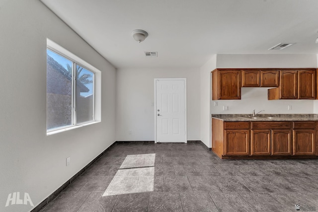 kitchen featuring visible vents, baseboards, and a sink