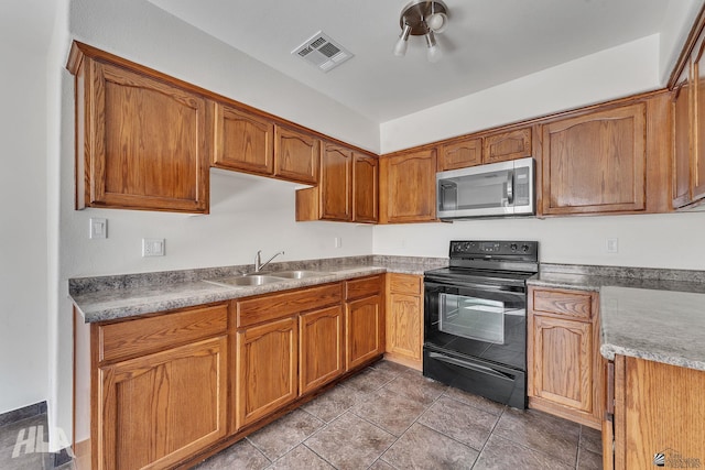 kitchen with visible vents, brown cabinets, black electric range, stainless steel microwave, and a sink