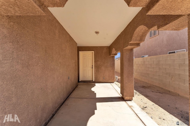 view of exterior entry with a patio area, fence, visible vents, and stucco siding