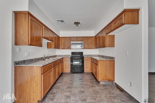 kitchen with stainless steel microwave, visible vents, brown cabinetry, black / electric stove, and a sink