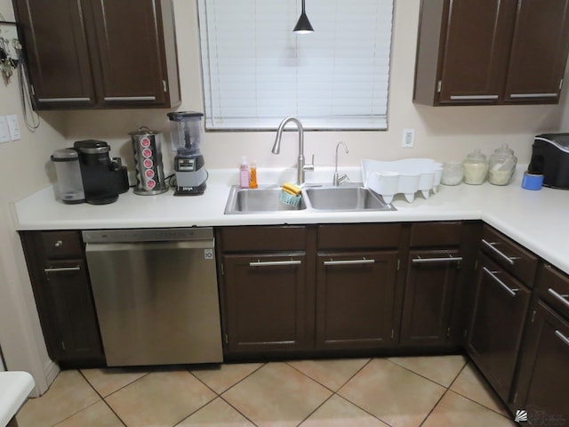 kitchen featuring dark brown cabinetry, sink, hanging light fixtures, stainless steel dishwasher, and light tile patterned flooring