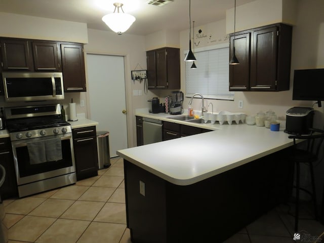 kitchen with sink, light tile patterned floors, decorative light fixtures, kitchen peninsula, and stainless steel appliances