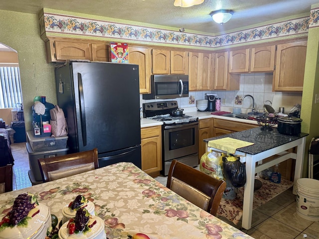 219 E Rio Sonora St, San Luis, AZ 85336 - kitchen with appliances with stainless steel finishes, light countertops, tile patterned floors, arched walkways, and a textured ceiling
