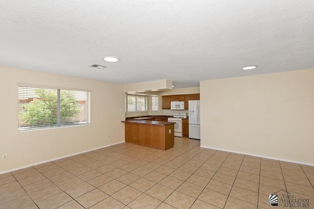 11279 E 26th Ln, Yuma, AZ 85367 - kitchen with white appliances, a peninsula, a textured ceiling, open floor plan, and light tile patterned flooring