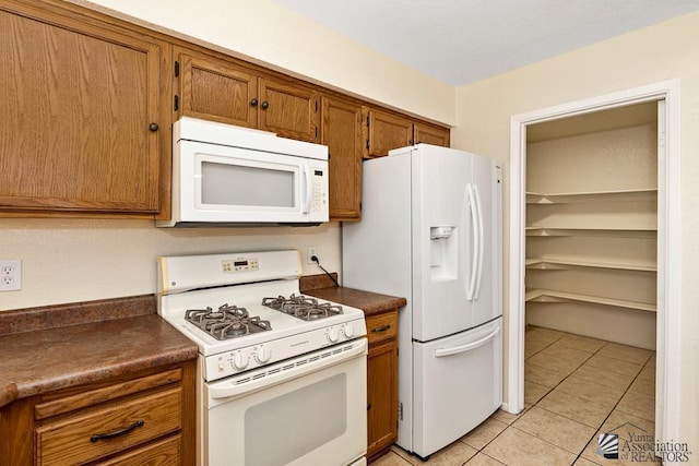 11279 E 26th Ln, Yuma, AZ 85367 - kitchen with white appliances, dark countertops, brown cabinetry, and light tile patterned floors