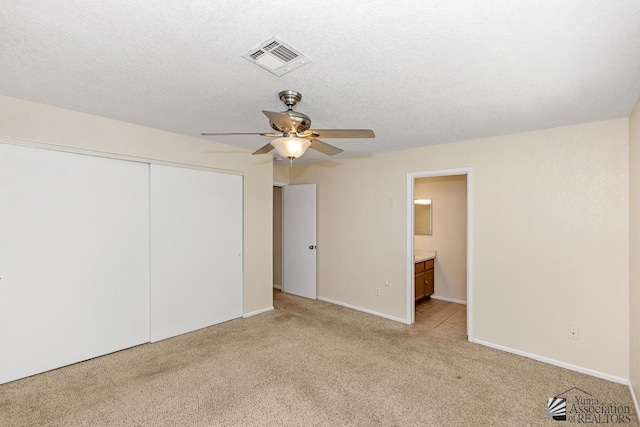 11279 E 26th Ln, Yuma, AZ 85367 - unfurnished bedroom featuring light carpet, a closet, ceiling fan, ensuite bath, and a textured ceiling