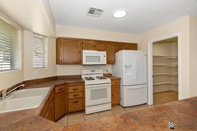 11279 E 26th Ln, Yuma, AZ 85367 - kitchen featuring white appliances, light tile patterned floors, brown cabinets, and dark countertops