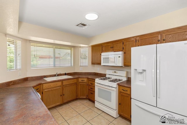 11279 E 26th Ln, Yuma, AZ 85367 - kitchen with white appliances, dark countertops, light tile patterned flooring, and brown cabinetry