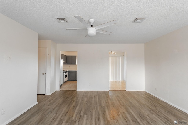 spare room with ceiling fan, light wood-type flooring, and a textured ceiling