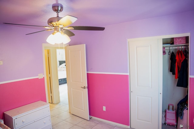 unfurnished bedroom with light tile patterned floors, ceiling fan, and a closet