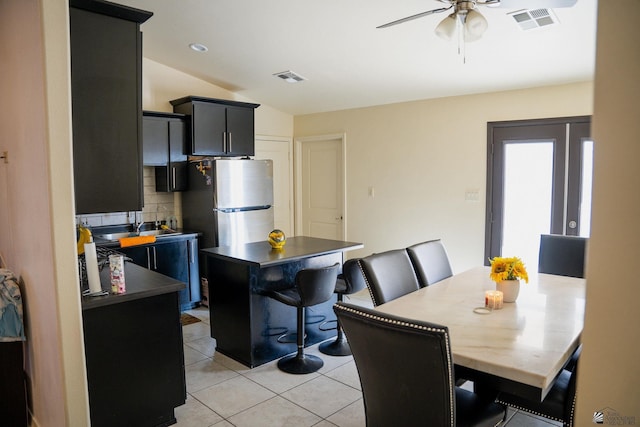 dining space with ceiling fan, vaulted ceiling, light tile patterned flooring, and visible vents