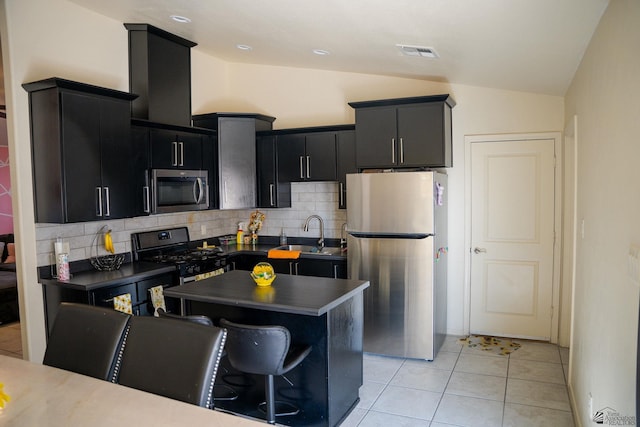 kitchen featuring visible vents, vaulted ceiling, a sink, dark cabinetry, and stainless steel appliances