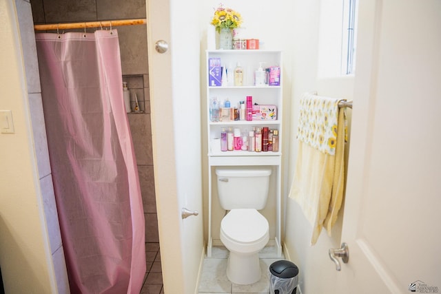 bathroom with a shower with shower curtain, tile patterned floors, and toilet