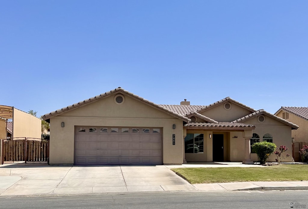 7841 E 36th Pl, Yuma, AZ 85365 - mediterranean / spanish-style home with concrete driveway, a garage, stucco siding, a chimney, and a tile roof