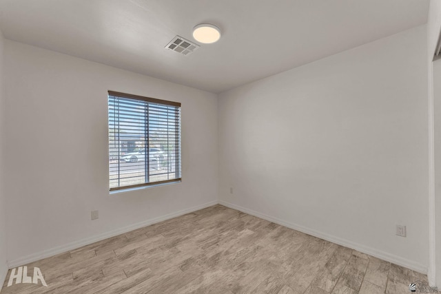 unfurnished room with light wood-style floors, visible vents, and baseboards