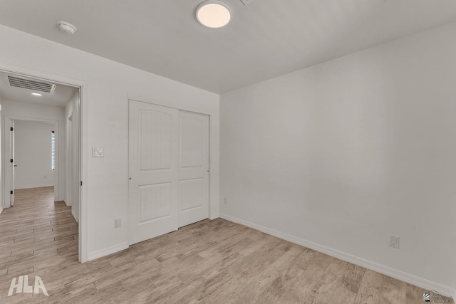 unfurnished bedroom featuring light wood-type flooring, baseboards, visible vents, and a closet