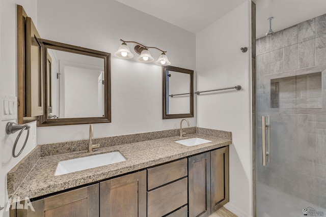 full bath featuring double vanity, a stall shower, and a sink