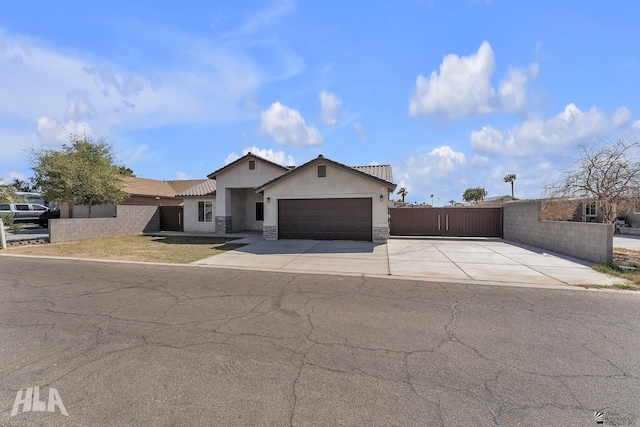 ranch-style house featuring stucco siding, fence, a garage, stone siding, and driveway