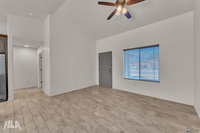 empty room featuring light wood-style floors, ceiling fan, high vaulted ceiling, and baseboards